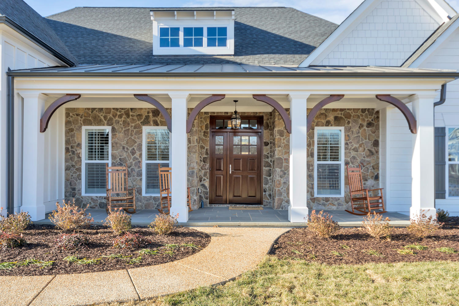 Exterior of a Craig Builders home in Oak Hill Farm. Rocking chairs sit on a wide column-lined porch.