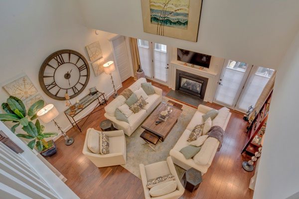 Shot looking down on the Villager Courtyard great room. Features warm lighting, wooden floors, comfy couches and a fireplace.